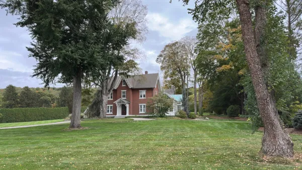Two-story brick house on large lot with green lawn and mature trees in Connecticut.