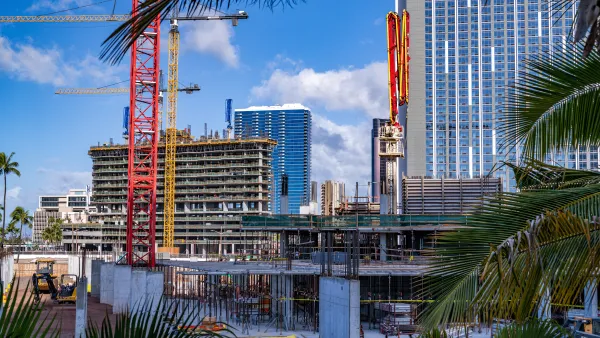 Cranes and apartment buildings, flanked by palm trees in Honolulu