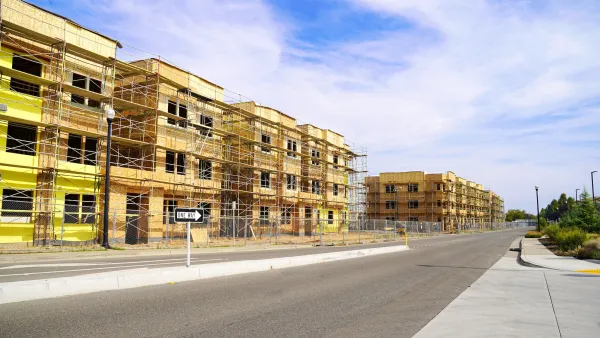 Wood-framed three-story apartment buildings under construction on a one-way street in California.