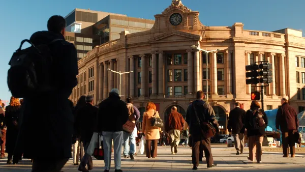 Neo-classical rounded South Station building with decorative clock on front and crowd walking in and out.