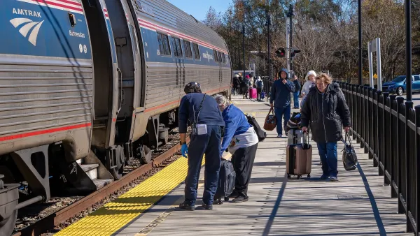 People with luggage on train platform next to silver Amtrak train in Selma, North Carolina.