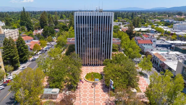 High-rise simple modernist Palo Alto,California City Hall building with open plaza lined by trees in front.