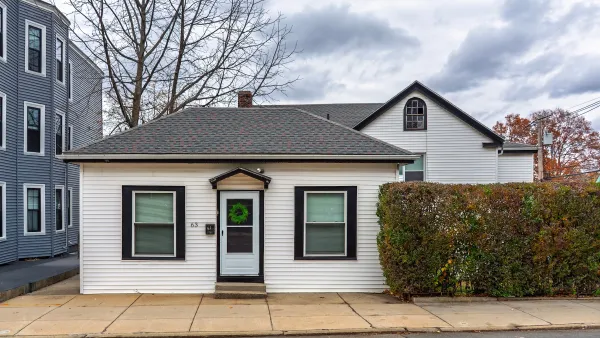 Small white clapboard home in Boston, Massachusetts with green wreath on black front door.