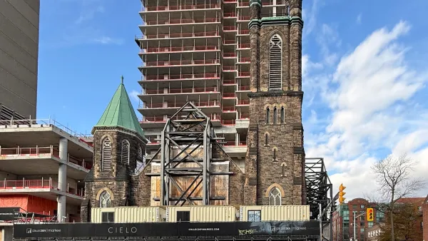 Multi-story apartment building under construction directly behind old stone church in Toronto, Canada.