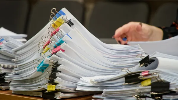 Close-up on stacks of papers clipped together with multicolored alligator clips on a desk.