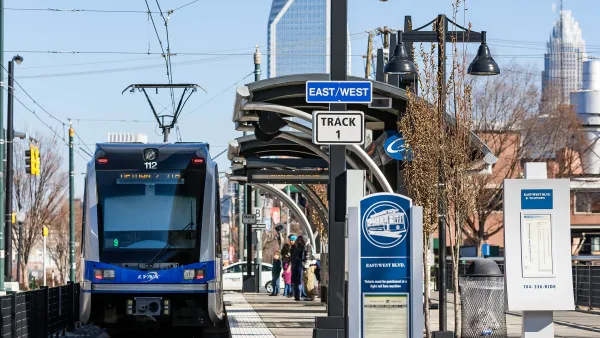A sleek light rail glides through Charlotte, NC, carrying commuters and visitors past busy neighborhoods, skyline views.