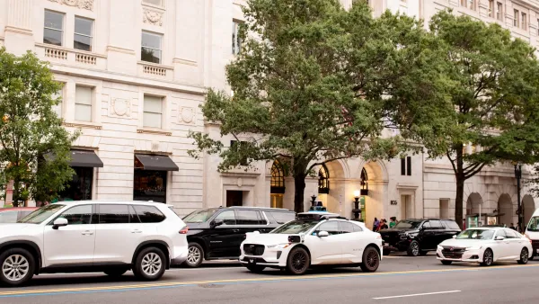 White Waymo cars lined up next to a white neoclassical building in Washington D.C.