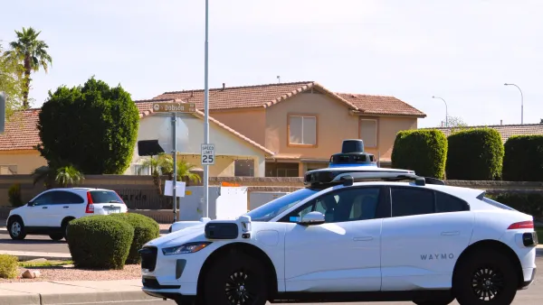 White Waymo robotaxi in fron tof Southwestern Spanish revival house in Phoenix, Arizona.