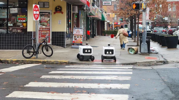 Two small white robots at crosswalk in Hoboken, New Jersey.