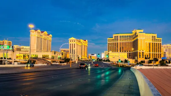 Blurred cars speeding on highway with Las Vegas strip skyline in background.