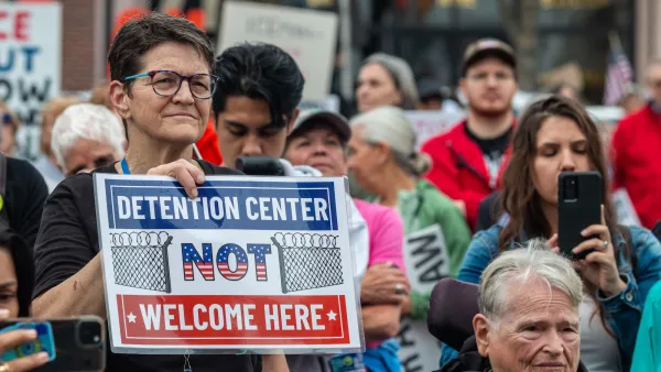 Woman in crowd holding sign saying "Detention center NOT welcome here" at protest against ICE detention center in Monroe, Georgia.