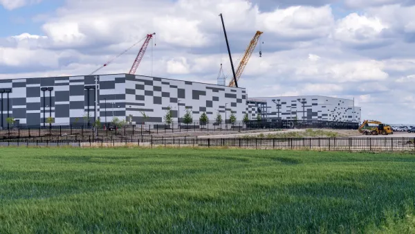 Exterior shot of the Skybox Power Campus data center building in Hutto, Texas with cranes visible on a partly cloudy day.