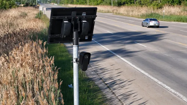 Black Flock camera mounted on post next to suburban roadway in Michigan.