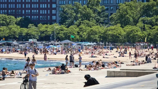 People sunbathing and hanging out on concrete seawall and sandy beach on Lake Superior in Chicago, Illinois.