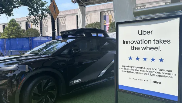 Black Uber self-driving car on display with sign.