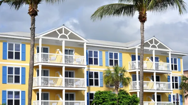 Colorfull light yellow and blue apartment building with tall palm trees in front in Florida.