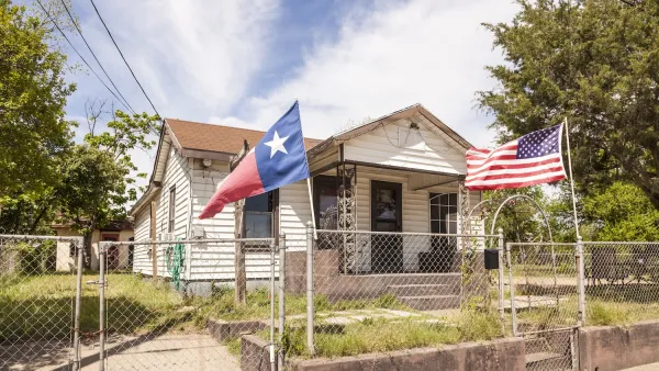 Small home with Texas and USA flags in front yard.