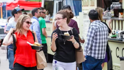 Food truck customers holding food with food trucks in background