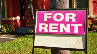 "For Rent" sign in yard of red building