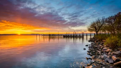 Colorful sunset viewed from rockly shoreline on Chesapeake Bay with dock in distance