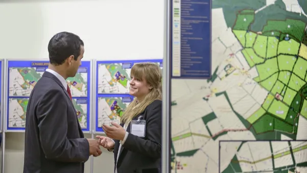 Man and woman talking in front of project presentation board at public meeting.