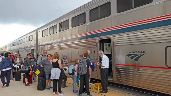 Passengers board an Amtrak train under a cloudy sky.