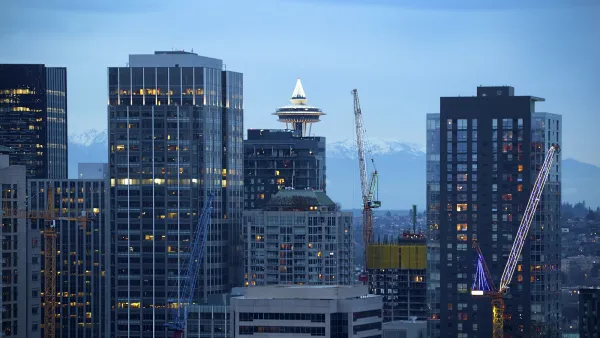 Seattle skyline at dusk with Space Needle and yellow construction cranes.