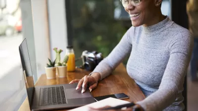 Woman sitting at countertop with laptop facing window