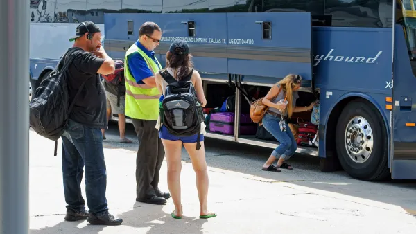 Three passengers and driver stand next to Greyhound bus at station with bottom luggage compartment open.