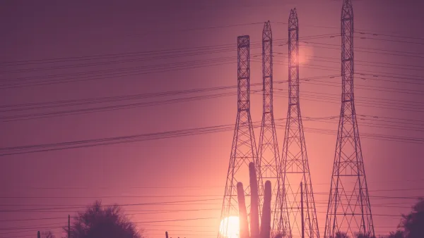 Tall power line towers against sunset with saguaro cacti at bottom in Arizona.