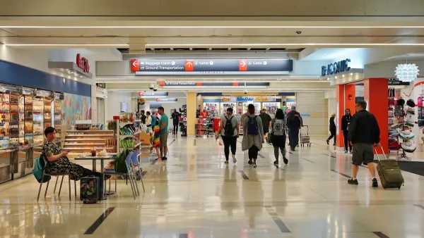 People walk through Philadelphia International Airport. There is a convince store on the right. 
