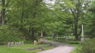 Gravestones along pathway in green Mount Auburn Cemetery