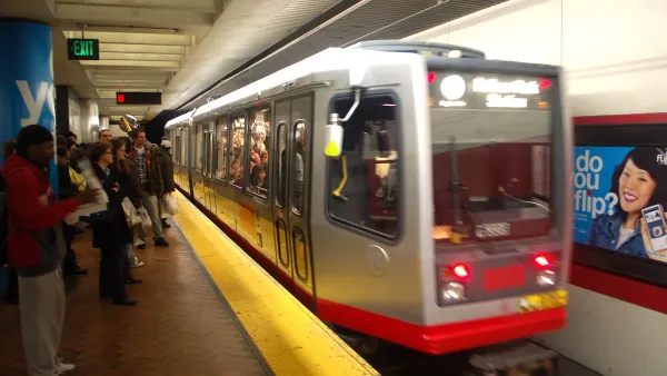 Blurred red Muni train passing by platform at underground station in San Francisco.