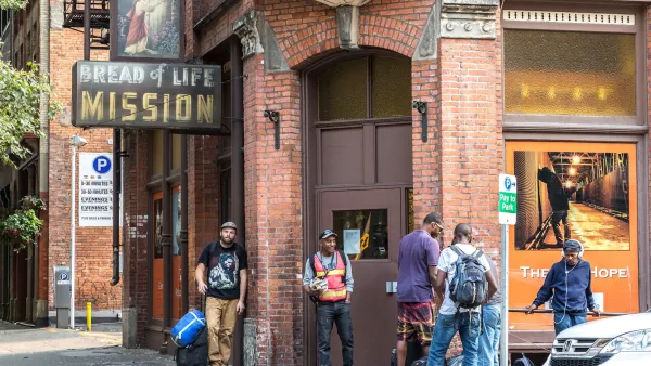 Several men stand waiting in front of Bread of Life Mission brick building in Seattle, Washington.