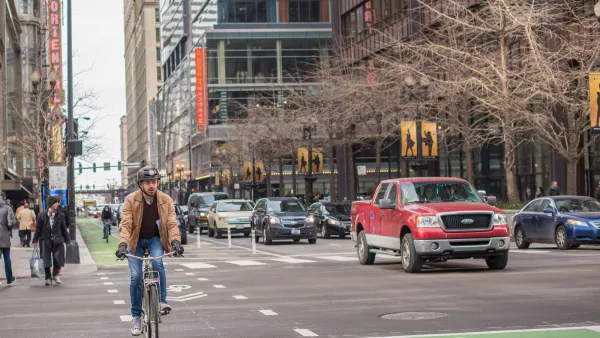 Chicago street with red truck and cyclist wearing helmet riding in green painted bike lane.