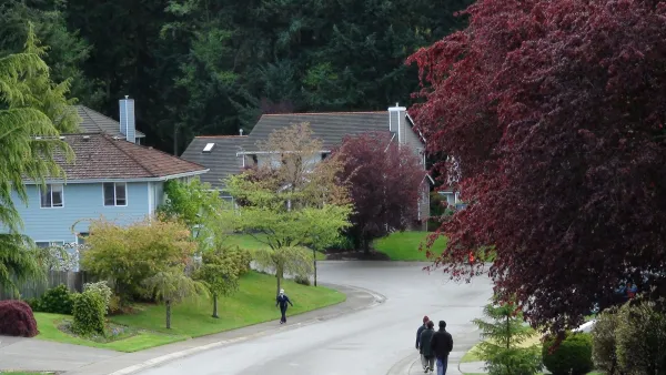 Three people walking or jogging on sidewalks in residential neighborhood with large homes and leafy trees.