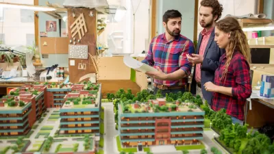 Three planners or architects standing over a model of buildings and greenery and discussing