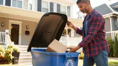 Man dropping cardboard box in blue curbside recycling bin