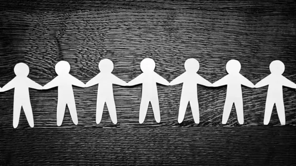 Cutout paper people on wooden table and artistic shadows 