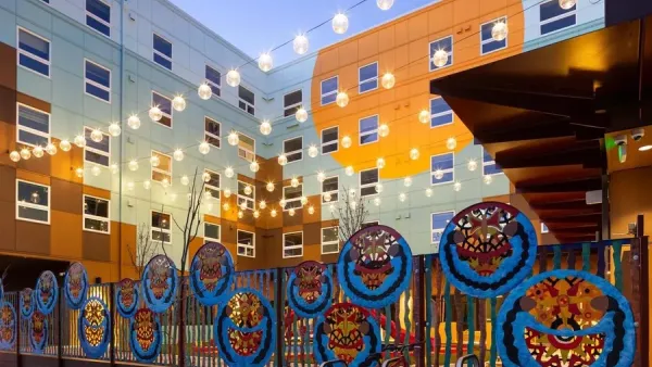 Colorful modern affordable housing apartment building in Seattle, Washington with bistro lights strung across yard at dusk.