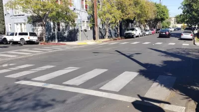 A white crosswalk painted by Crosswalk Collective LA in Los Angeles, California.